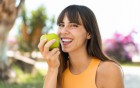 Lächelnde Frau mit einem Apfel in der Hand.