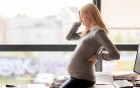 Eine Schwangere Frau im Office, die sich mit der Hand am Kopf hält